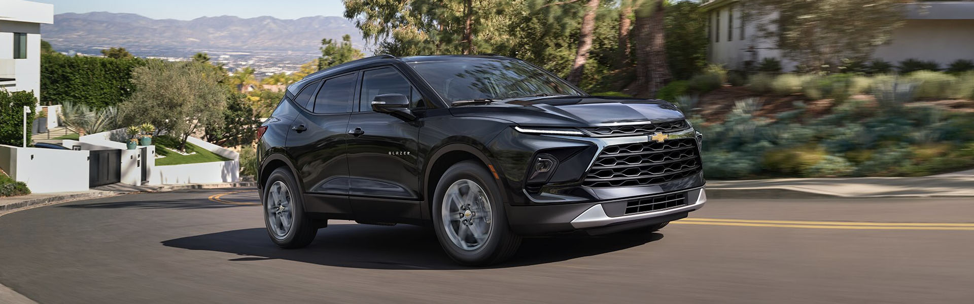 2025 Chevrolet Blazer black midsize SUV driving on a road.