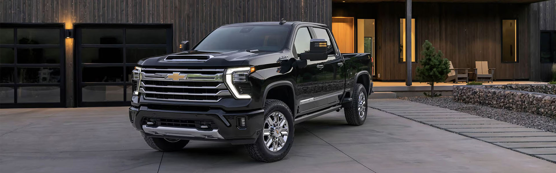 2026 Chevrolet Silverado HD parked outside a modern home, featuring a sleek black exterior and chrome accents.